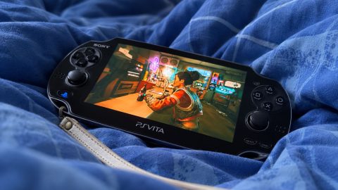 PS Vita OLED posée sur une couette bleue, avec Cyberpunk 2077 affiché à l’écran.